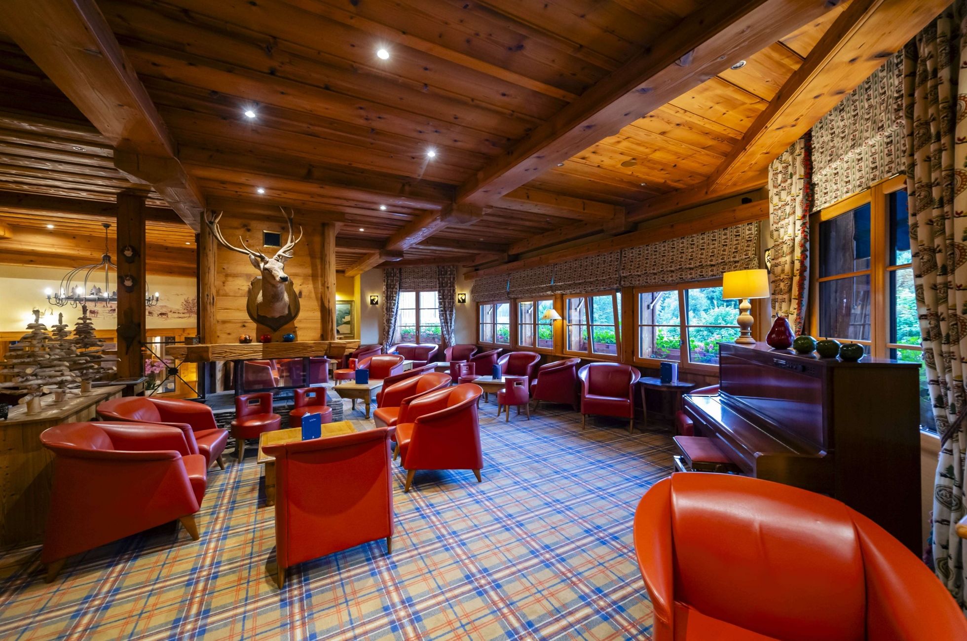 Vue panoramique du bar lounge et salon de l’hôtel Les Bas Rupts, avec boiseries et fauteuils rouges.